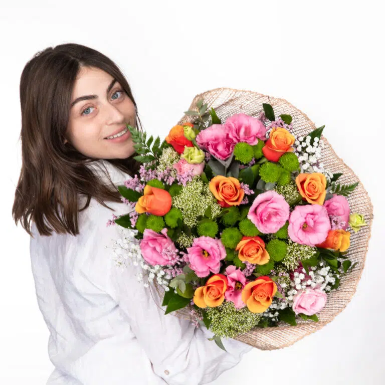 תמונה של דוגמנית מביטה מהצד ומחזיקה זר פרחים צבעוני אהבה בשדות ומחייכת